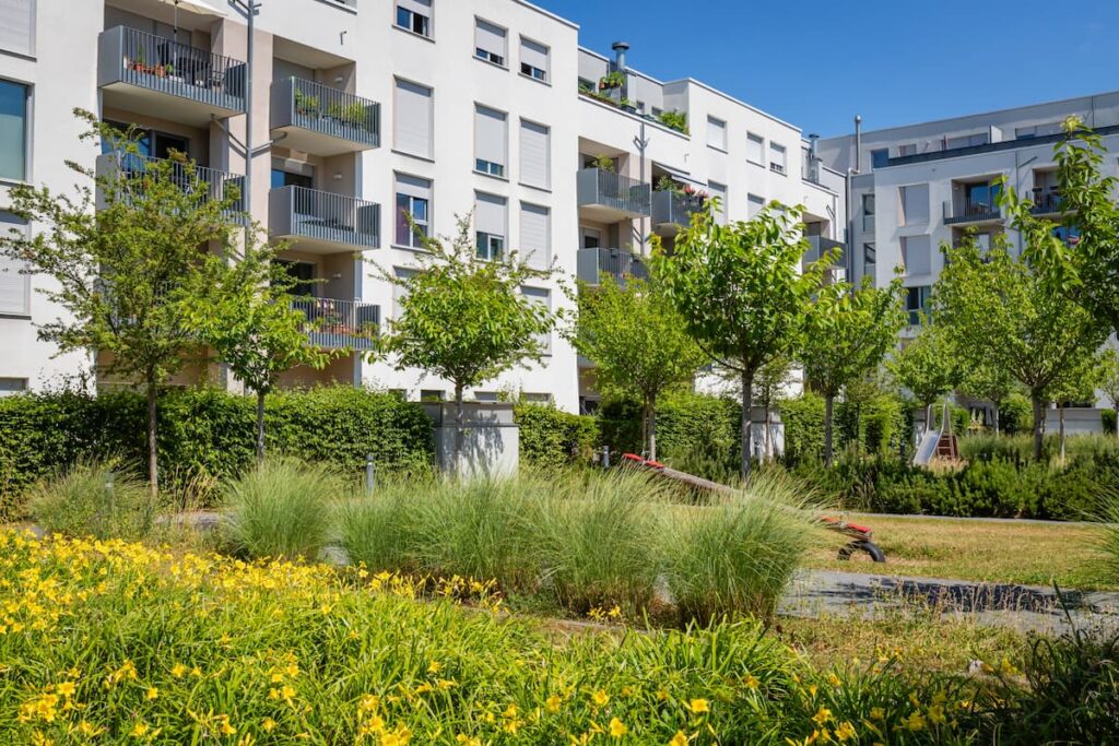 Well-maintained exterior of a multi-family apartment building with lush green landscaping, highlighting the value of preventative property maintenance.